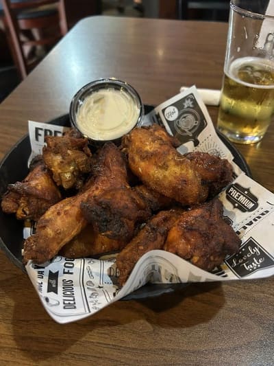 A basket of Double D's slow-cooked chicken wings with a cold beer